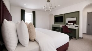 A bedroom with a bed, a desk, a chair, a television, and a door.
