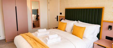 Quarto de hotel com cama, mesa de cabeceira, guarda-roupa e espelho.
