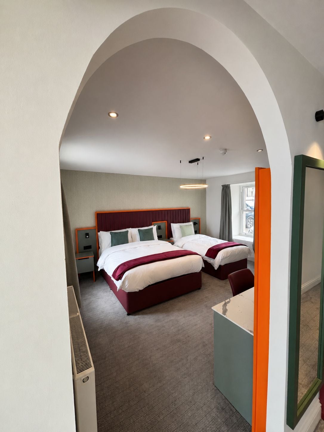 A hotel room with two beds, a large mirror, and a view of the outside.