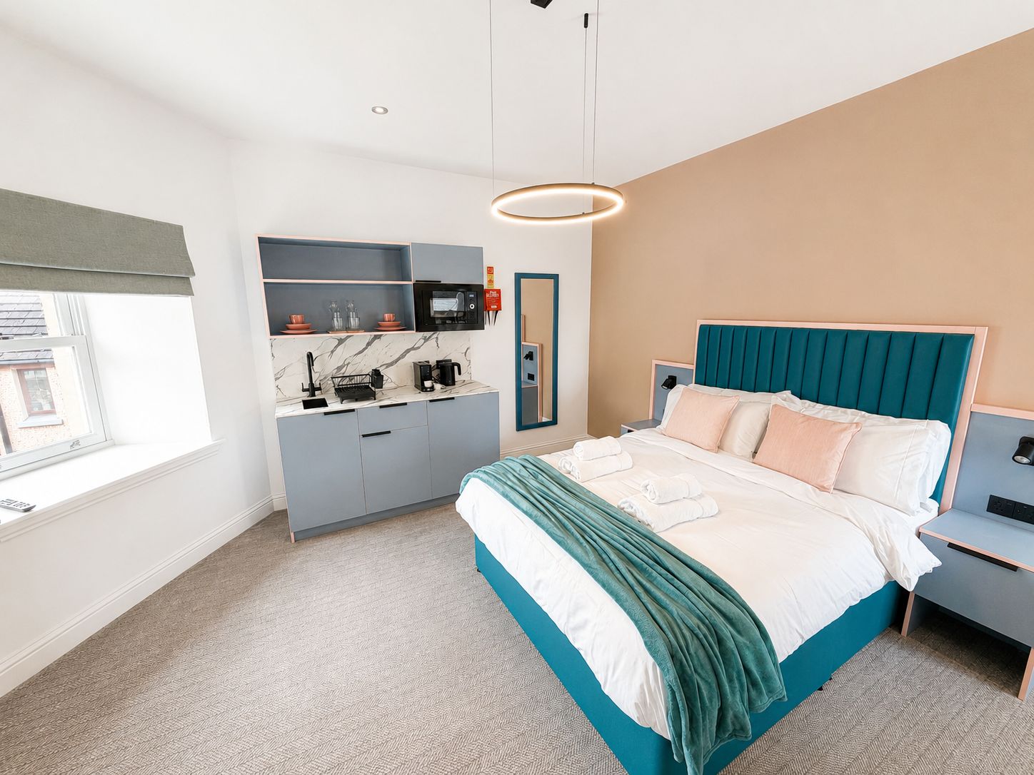 Habitación de hotel moderna con cama, escritorio, microondas integrado y ventana con vistas.