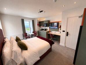 A hotel room with a bed, a desk, a chair, a television, and a view of the outdoors.