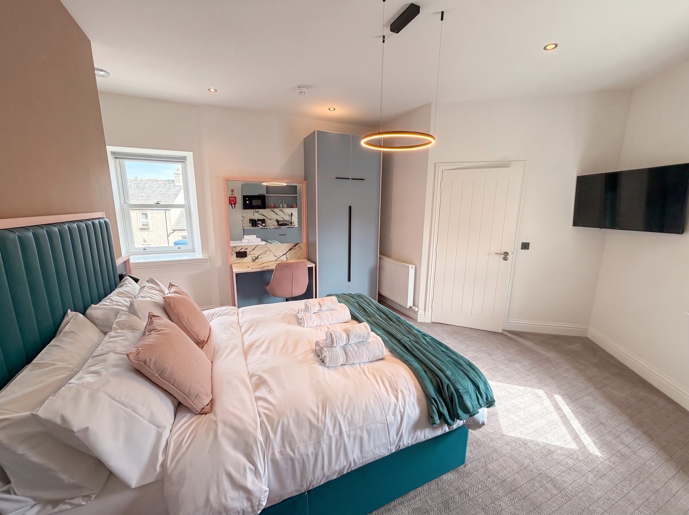 A bedroom with a bed, a wardrobe, a television, and a window.