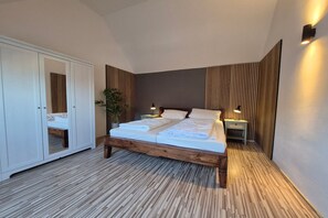 A bedroom with a bed, wardrobe, bedside tables, and a potted plant. - Familienfreundliches Ferienhaus mit Garten im Hafendorf Müritz (Rechlin)
