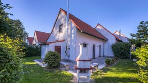 Ein zweistöckiges Haus mit rotem Ziegeldach, umgeben von Grünflächen und einem gepflegten Rasen.