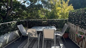 An outdoor patio with a table and chairs, surrounded by a patterned rug, and a 'Welcome' sign. - House Sleeps 8 With Balcony (London)