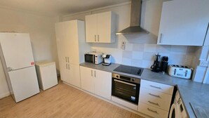 A compact kitchen with white cabinets, a microwave, a coffee maker, an oven, and a toaster. - House Sleeps 8 With Balcony (London)