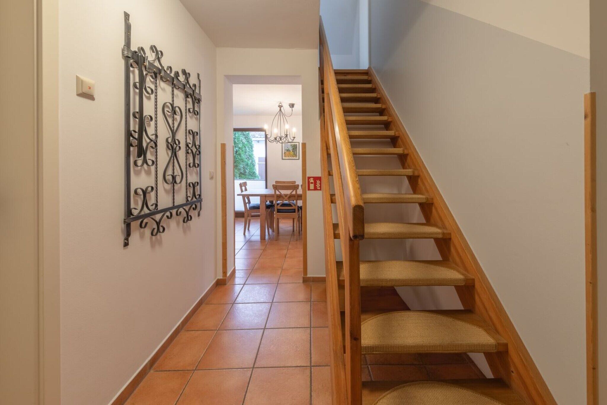 A staircase with wooden steps and woven carpet, leading to a dining area with a table and chairs.