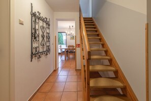 A staircase with wooden steps and woven carpet, leading to a dining area with a table and chairs. - Geräumiges Ferienhaus für Familie im Hafendorf Müritz Rechlin (Rechlin)