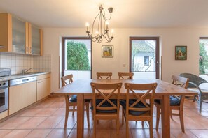 Een moderne keuken met een eetgedeelte, met een grote tafel, houten stoelen en een kroonluchter.