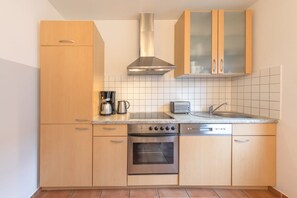 A compact kitchen with a stove, oven, coffee maker, toaster, and a dishwasher. - Geräumiges Ferienhaus für Familie im Hafendorf Müritz Rechlin (Rechlin)