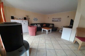 Ein Wohnzimmer mit einer Couch, einem Couchtisch, einem Fernseher und einer Küchenzeile mit Schränken und einer Arbeitsfläche.