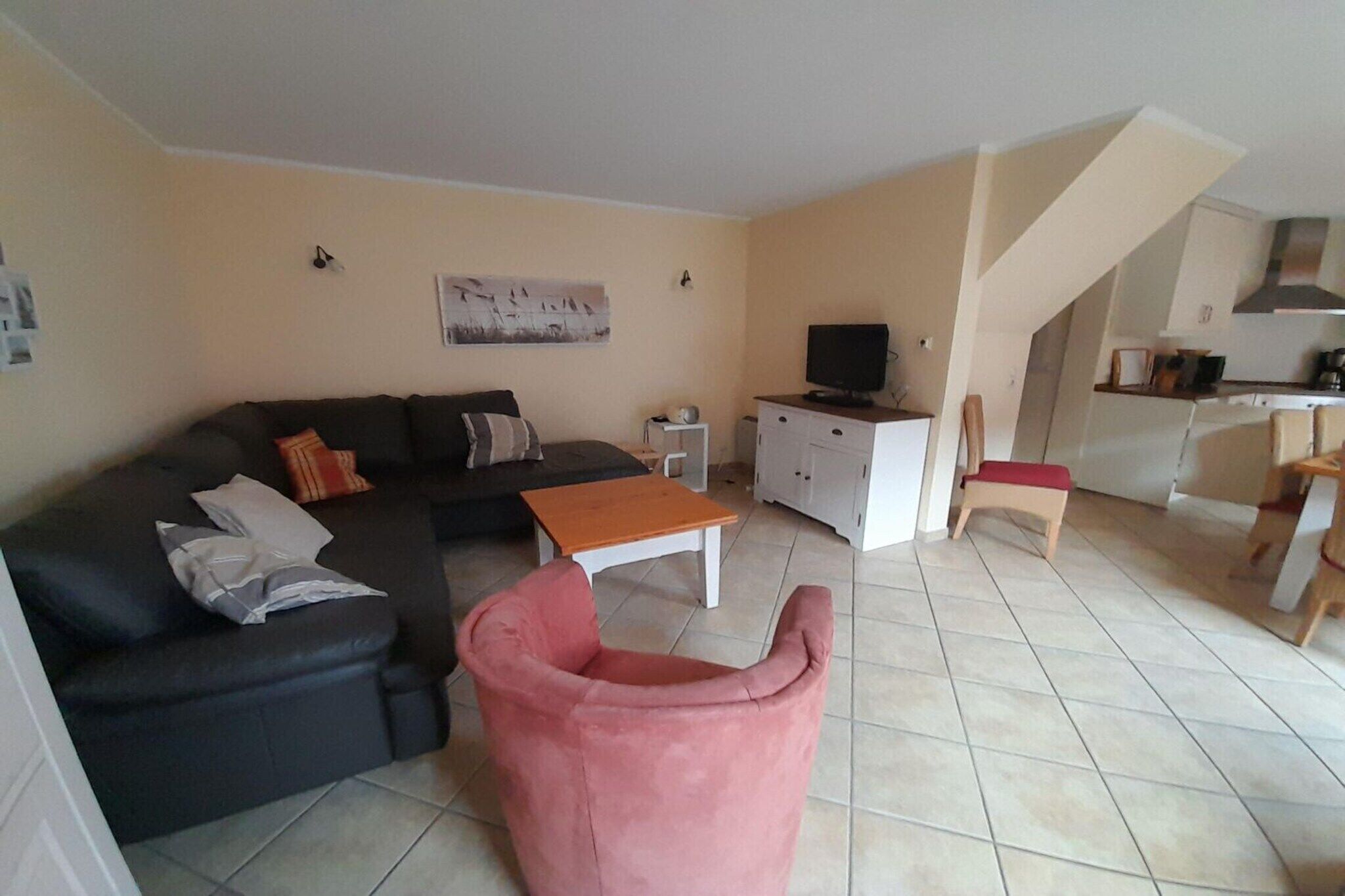 Uma sala de estar com sofá, mesa de centro, televisão e um espaço de jantar com cadeira e mesa.