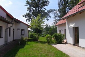 Ein Innenhof mit zwei Gebäuden, einer Rasenfläche und Bäumen.