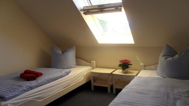 Un alojamiento pequeño y con una sola habitación, con dos camas, una mesita y una ventana.