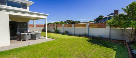 A modern house with a covered patio, a well-maintained lawn, and a wooden fence.