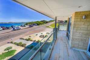 A balcony with a view of a coastal road and beach.