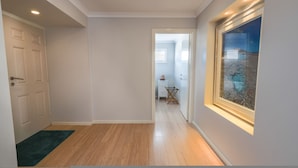 A hallway with a wooden floor, a door on the left, and a window on the right. - West Beach House in West Beach (Esperance)