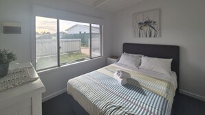 A bedroom with a bed, a nightstand, a window, and a wall-mounted artwork. - Esperance Little Units 1 (Esperance)