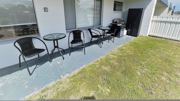 A covered patio with outdoor seating, a grill, and a fenced yard. - Esperance Little Units 1 (Esperance)