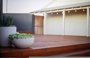 Eine Holzterrasse mit einem Blumentopf und einer weißen Schale darauf.