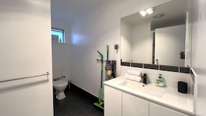 A modern bathroom with a toilet, sink, and mirror. - Little Emily in Esperance (Esperance)