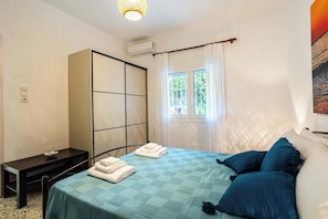 A bedroom with a bed, a desk, a wardrobe, and a window with curtains. - Charming Beachfront Haven, Steps from the Beach (Kiparissia)