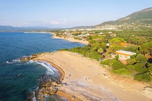 A coastal landscape with a beach, rocky shoreline, and buildings with a mix of architecture styles. - Charming Beachfront Haven, Steps from the Beach (Kiparissia)