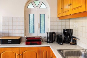 Eine Küche mit einer Brotmaschine, einem roten Toaster, einer Kaffeemaschine und einem Wasserkocher.