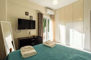 A bedroom with a bed, a TV, a dresser, a wardrobe, and a window with curtains. - Kyparissia Modern Home, Serene Views - Calm Vibes (Kiparissia)