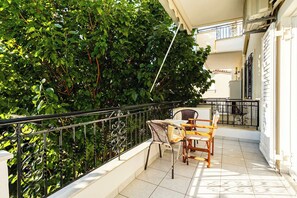 Un balcon agrémenté d’une table et de chaises, entouré d’un luxuriant feuillage verdoyant.