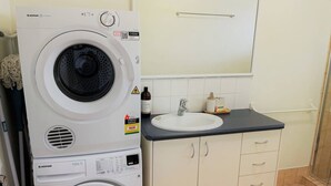A compact laundry area with stacked washing machines and a sink.