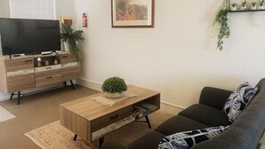 A living room with a TV, wooden cabinet, sofa, and a framed picture on the wall.