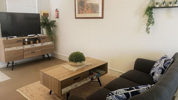 A living room with a TV, wooden cabinet, sofa, and a framed picture on the wall. - Esperance Little Units 4 (Esperance)