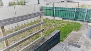 A fenced outdoor area with a wooden bench, a concrete pathway, and a green fence in the background. - Esperance Little Units 4 (Esperance)