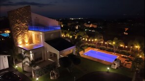 Une maison moderne dotée d’une piscine, d’un éclairage extérieur et offrant une vue sur le quartier environnant.