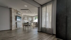 Eine moderne Küche mit Steinwand, einem Essbereich mit Tisch und Stühlen sowie einem großen Fenster mit Vorhängen.