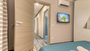 Ein Hotelzimmer mit einem Bett, einem Fernseher, einer Klimaanlage und einem Badezimmer mit Dusche.