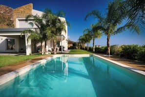 A modern house with a swimming pool, surrounded by palm trees and a clear blue sky. - Villa Skyline: Design, Pool, Ocean View by Sicily Home Solutions (Castellammare del Golfo)