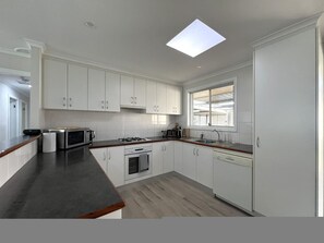 Eine moderne Küche mit weißen Schränken, einer schwarzen Arbeitsplatte, einem Oberlicht und einem Fenster.