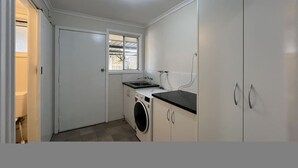 Eine kleine Küche mit Waschmaschine, Spüle und Fenster.