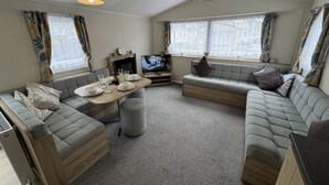 Un espacio habitable pequeño con un conjunto de sofás, una mesa de comedor y una televisión.