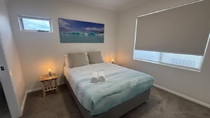 A bedroom with a bed, a nightstand, a painting, and a window. - Seabreeze Esperance in West Beach (Esperance)