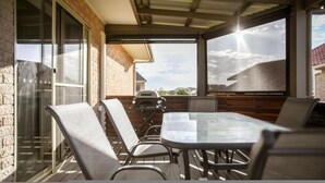 An outdoor patio with a glass enclosure, a table, and chairs. - Seabreeze Esperance in West Beach (Esperance)