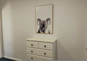 A room with a white dresser and a framed picture of a koala on the wall. - The Oceanaire in West Beach (Esperance)