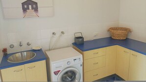 A laundry area with a washing machine, a sink, and a drying rack.