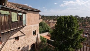A traditional building with a stone facade, a wooden balcony, and a view of a town with terracotta roofs. - La Juderia Segovia Lodging (Segovia)