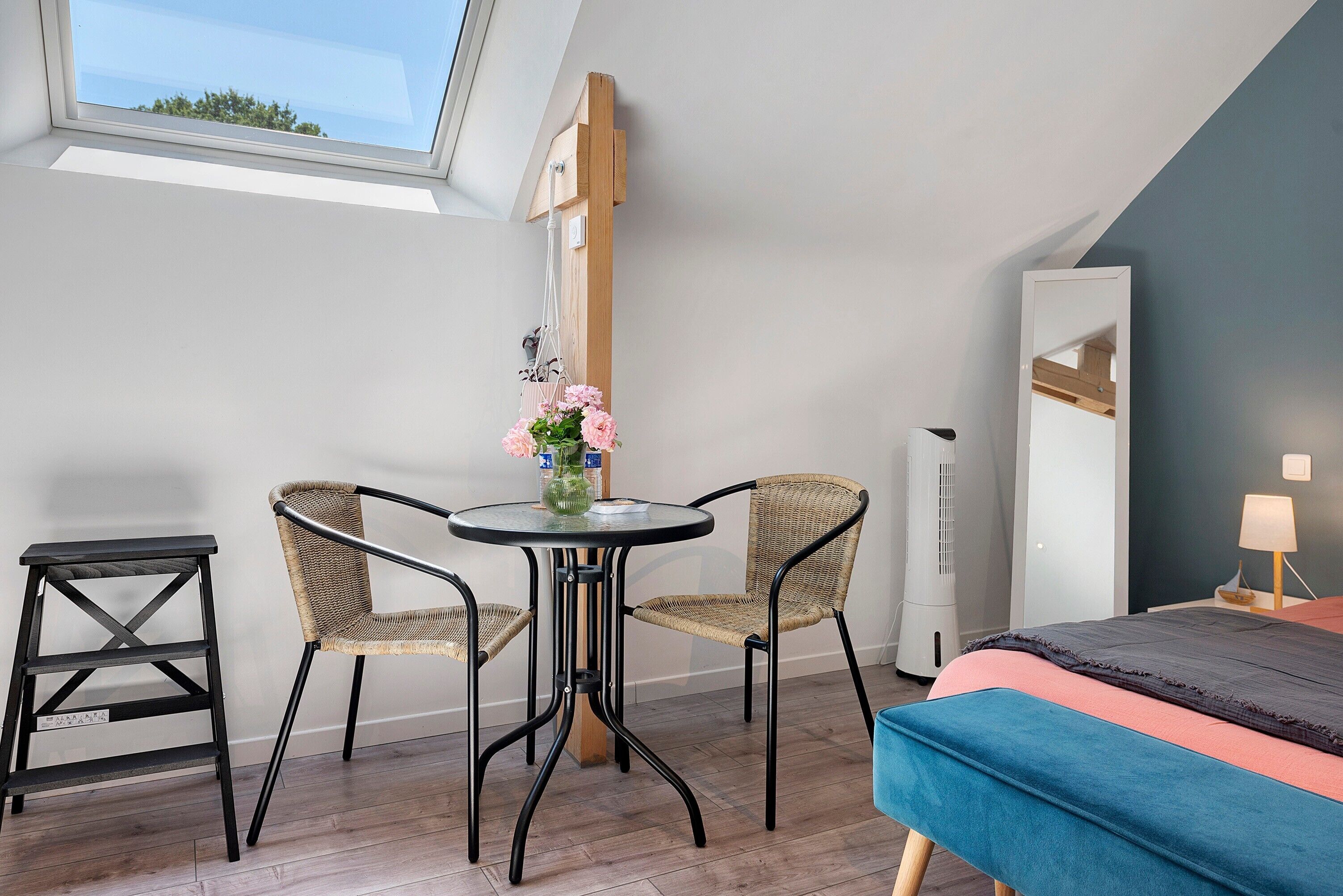 Une petite pièce moderne avec un puits de lumière, un lit, une table avec des chaises et un radiateur.