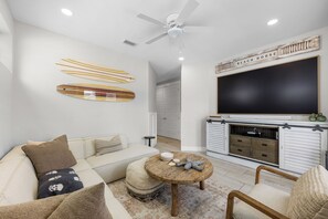 Ein modernes Wohnzimmer mit Sofa, Couchtisch und an der Wand montiertem Fernseher.