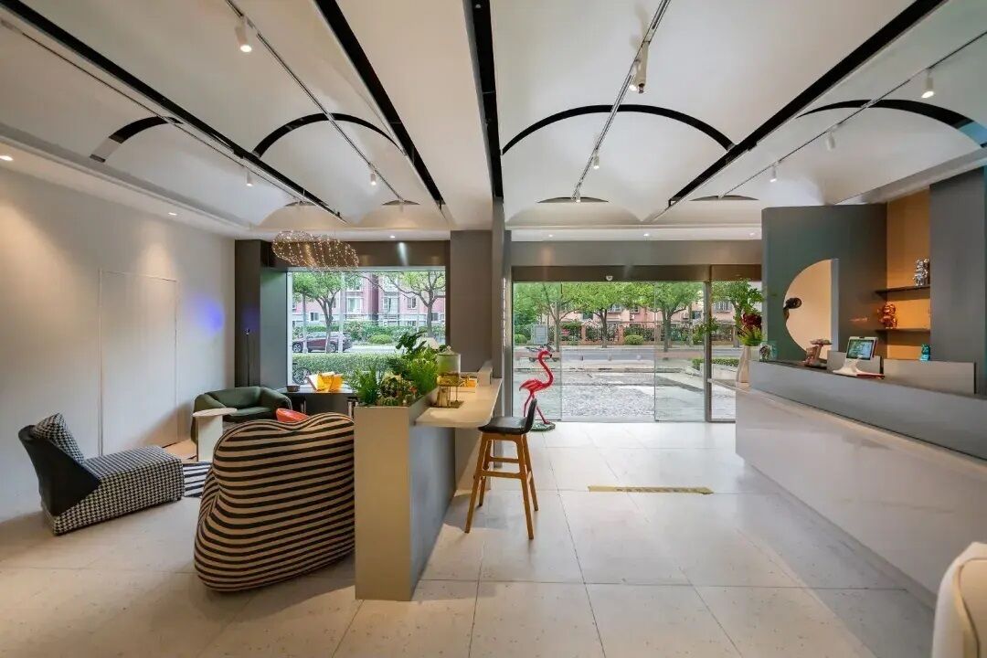 Un interior moderno con mostrador de recepción, zona de estar y vistas al exterior.