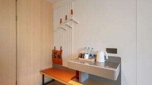 A modern bathroom with a bench, a towel rack, a sink with toiletries, and a mirror. - Sushi Light Luxury Hotel Xingzhuang (Shanghai)